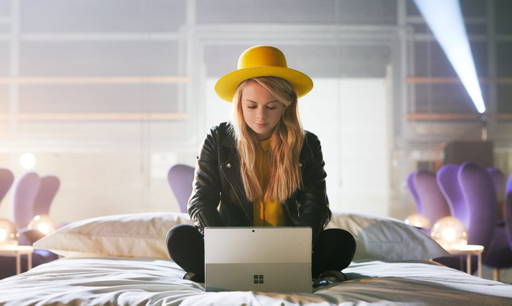 A woman with a yellow hat working on a Surface
