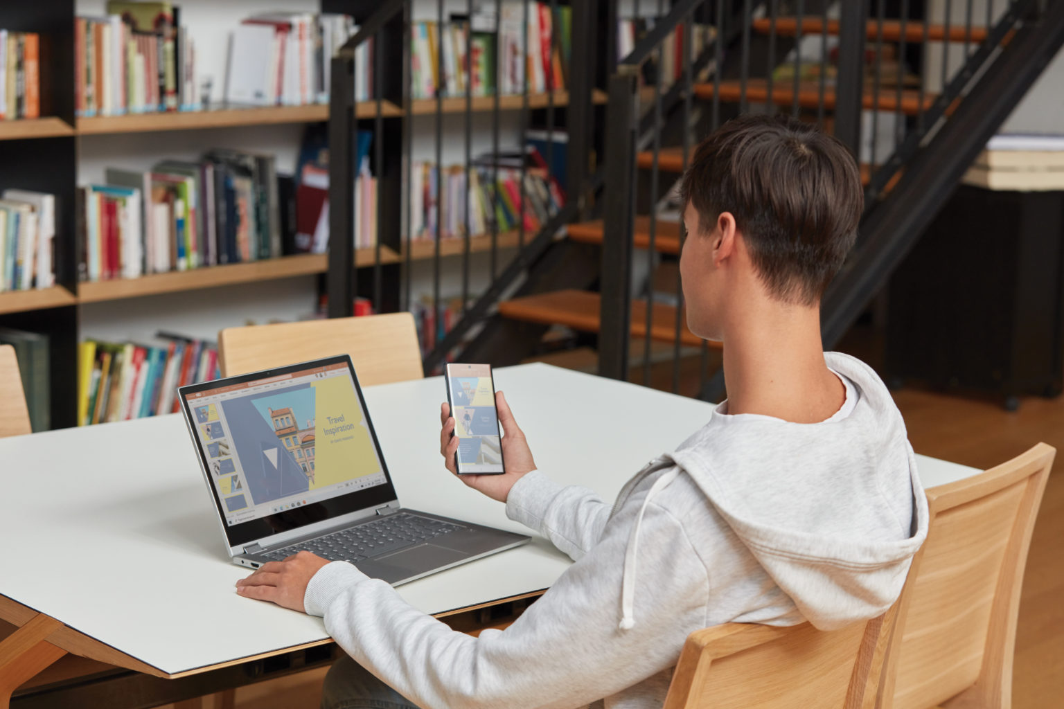 en mand ved hjælp af en bærbar computer sidder på toppen af en bog hylde