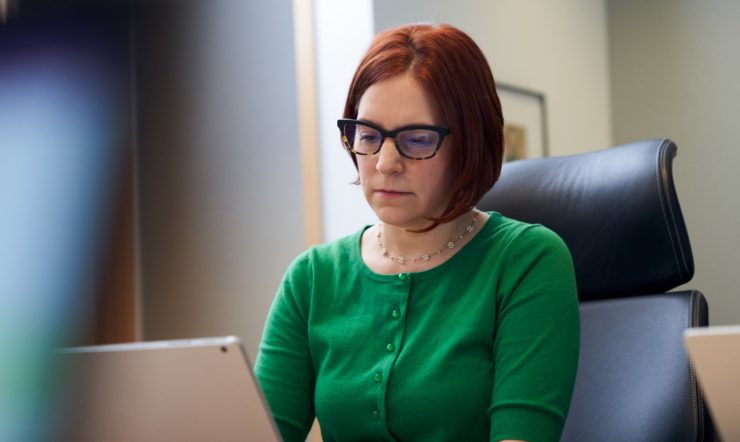 een vrouw zit aan een tafel en gebruikt een laptop