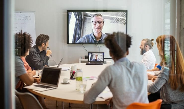een groep mensen die bij een bureau voor een venster zitten