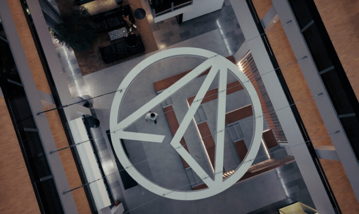 Aerial view looking down into a modern building atrium with a large geometric logo incorporated into the floor design.